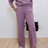 Person wearing a matching purple outfit with a sweater and pants on a plain background