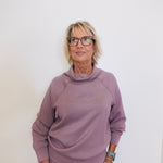 Woman wearing a mauve outfit against a white background