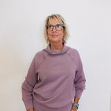 Woman wearing a mauve outfit against a white background