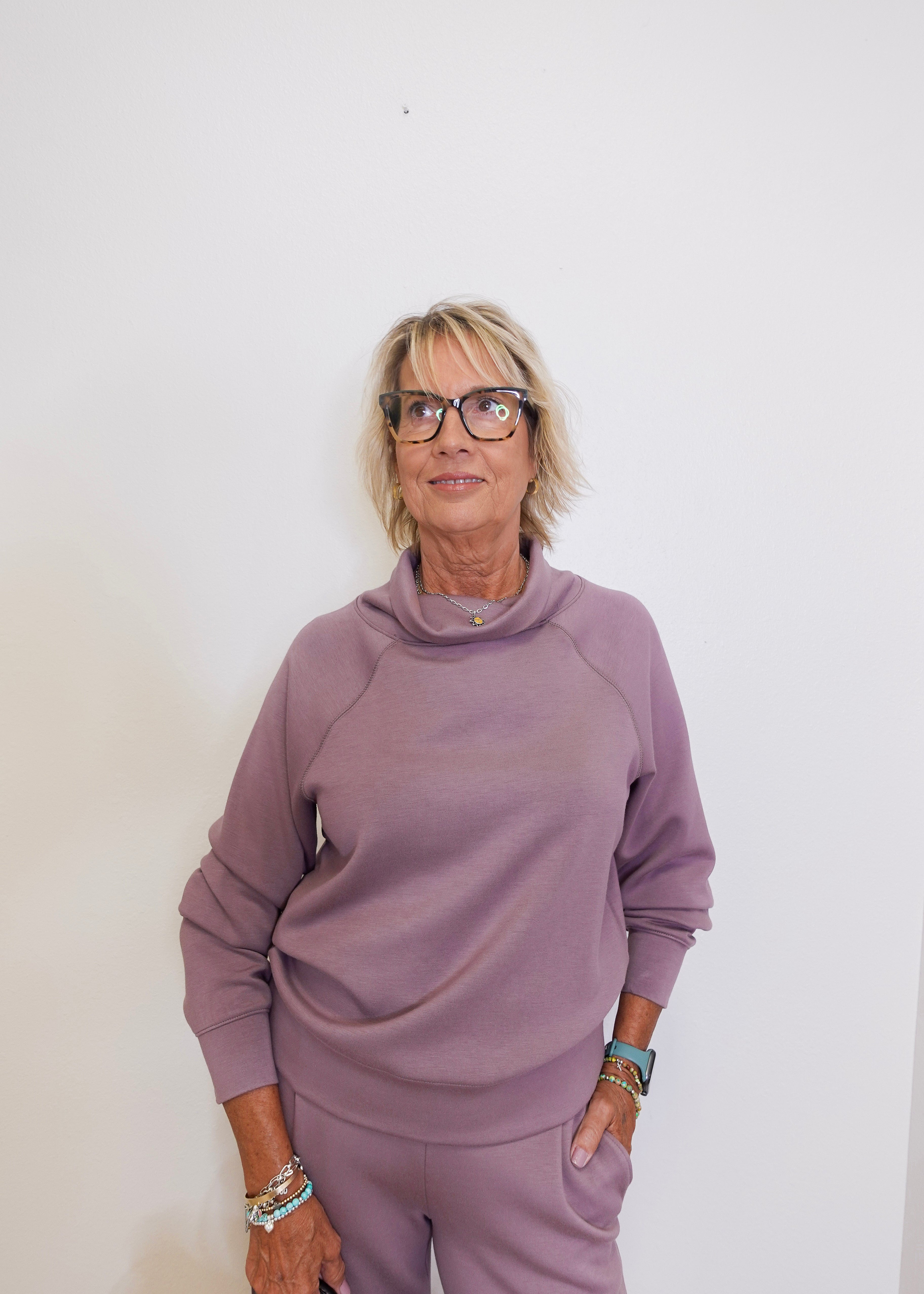 Woman wearing a mauve outfit against a white background