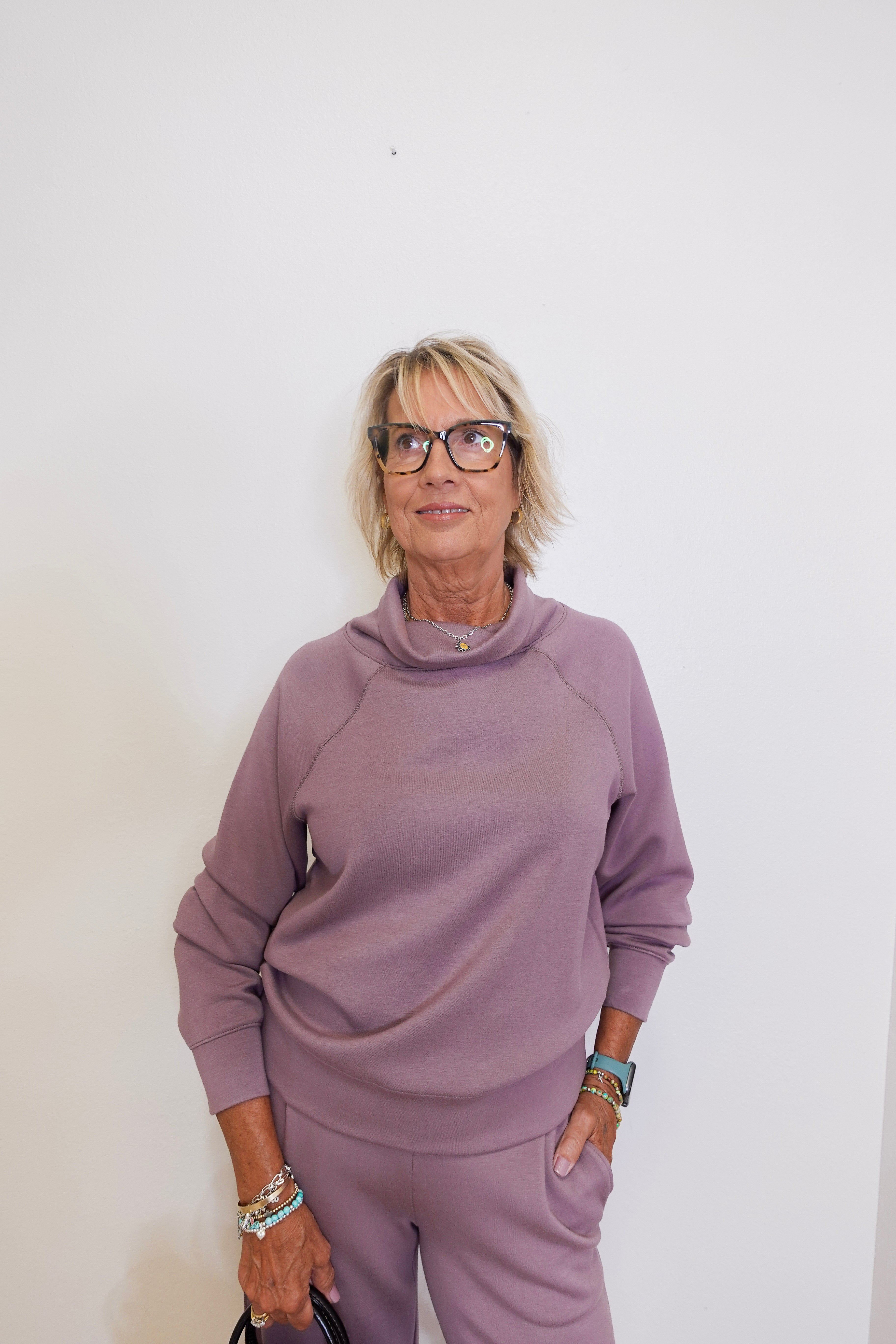 Woman wearing a mauve outfit against a white background