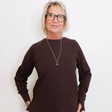 Woman wearing a brown sweater and glasses against a white background