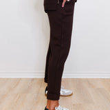 Person wearing black pants and white sneakers with black accents on a light wooden floor.