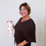 Woman holding a white tumbler with a floral design against a plain background
