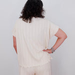 Person wearing a cream-colored outfit with a plain background