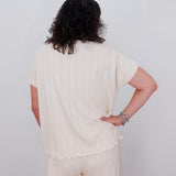 Person wearing a cream-colored outfit with a plain background