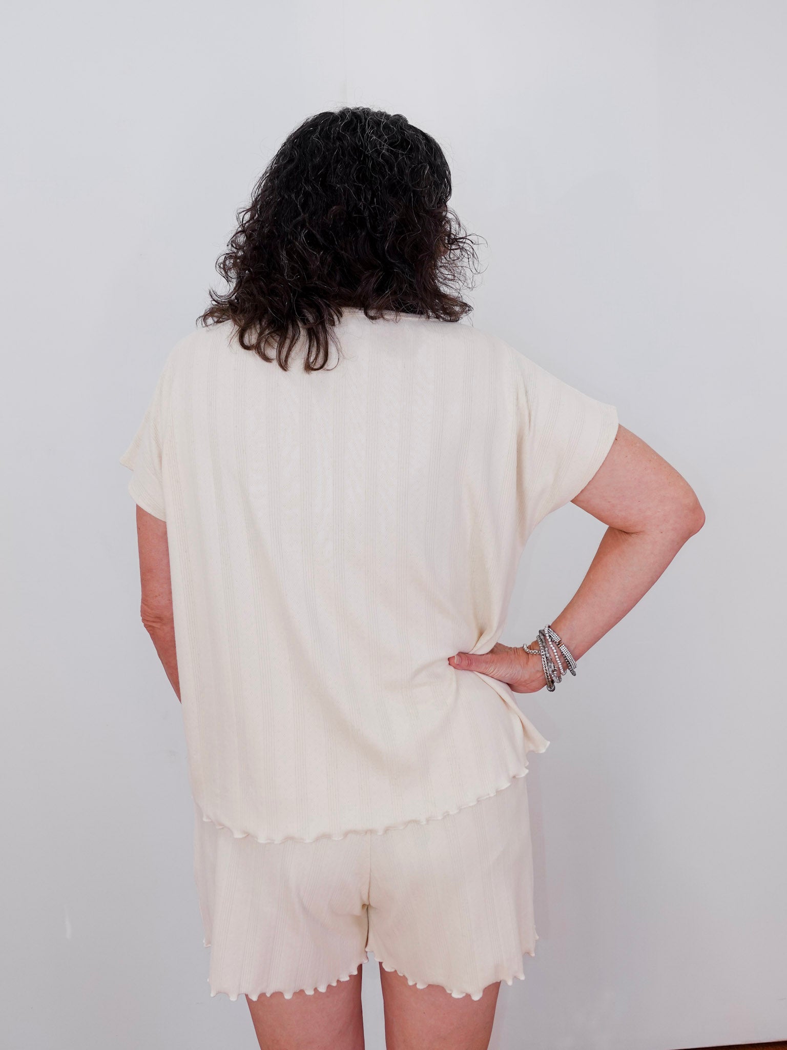 Person wearing a cream-colored outfit with a plain background