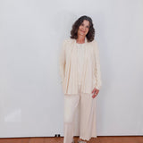 Woman in a beige outfit standing against a white wall