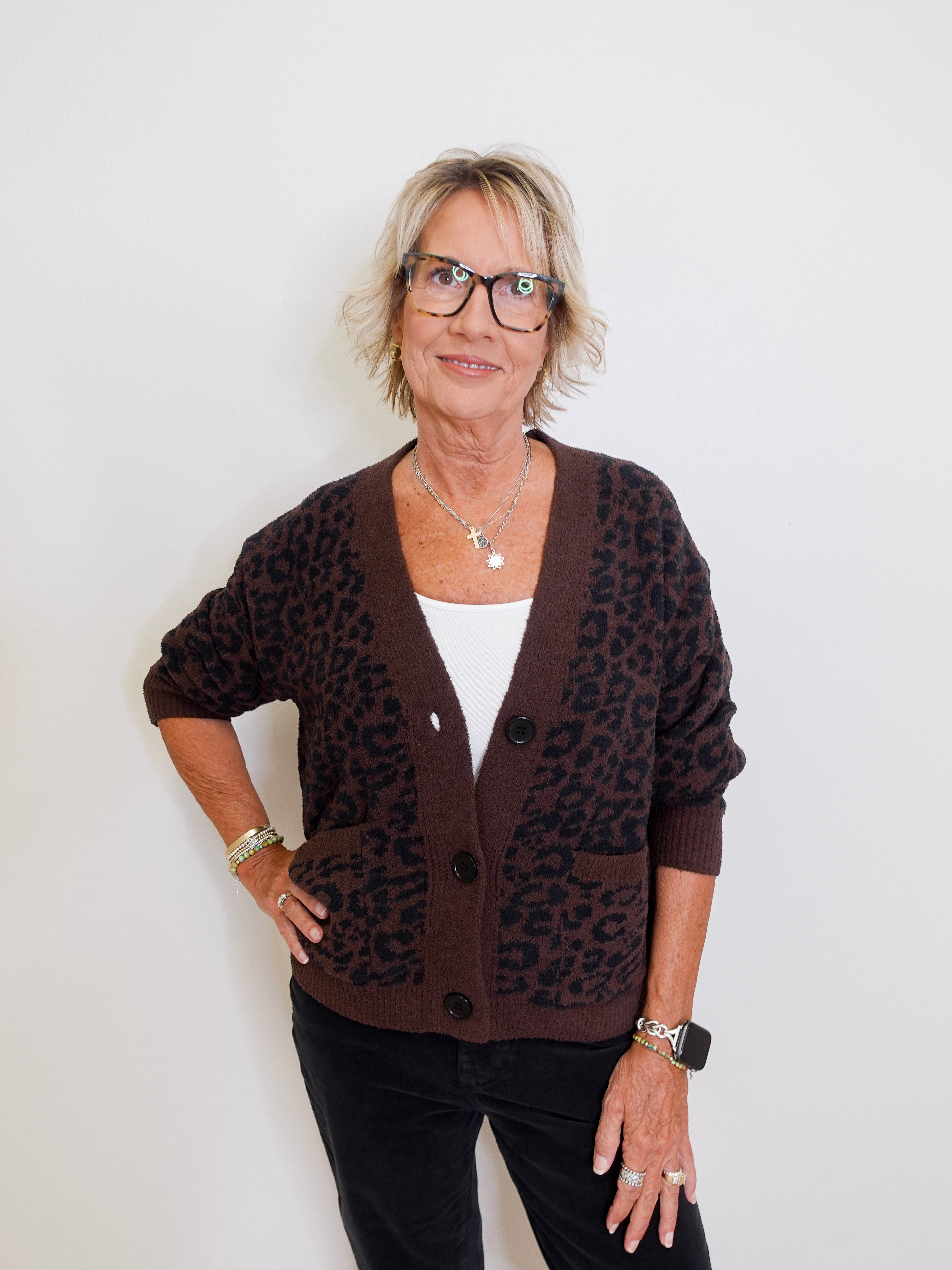 Woman wearing a brown leopard print cardigan against a white background