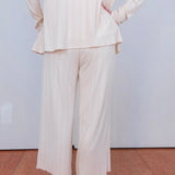 Person wearing a white suit with wide-leg pants on a plain background