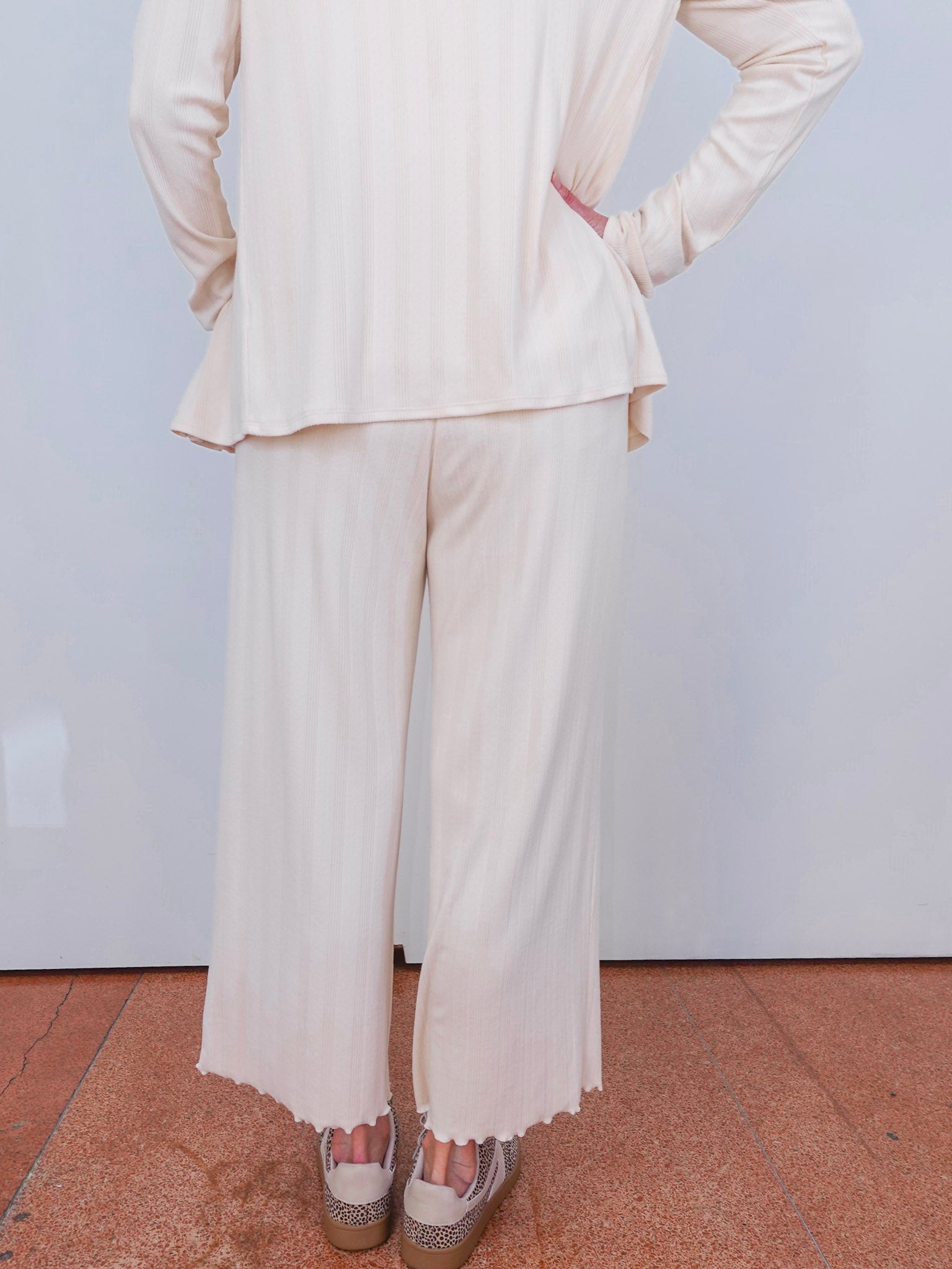 Person wearing a white suit with wide-leg pants on a plain background