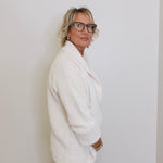 Person wearing a white sweater against a plain background