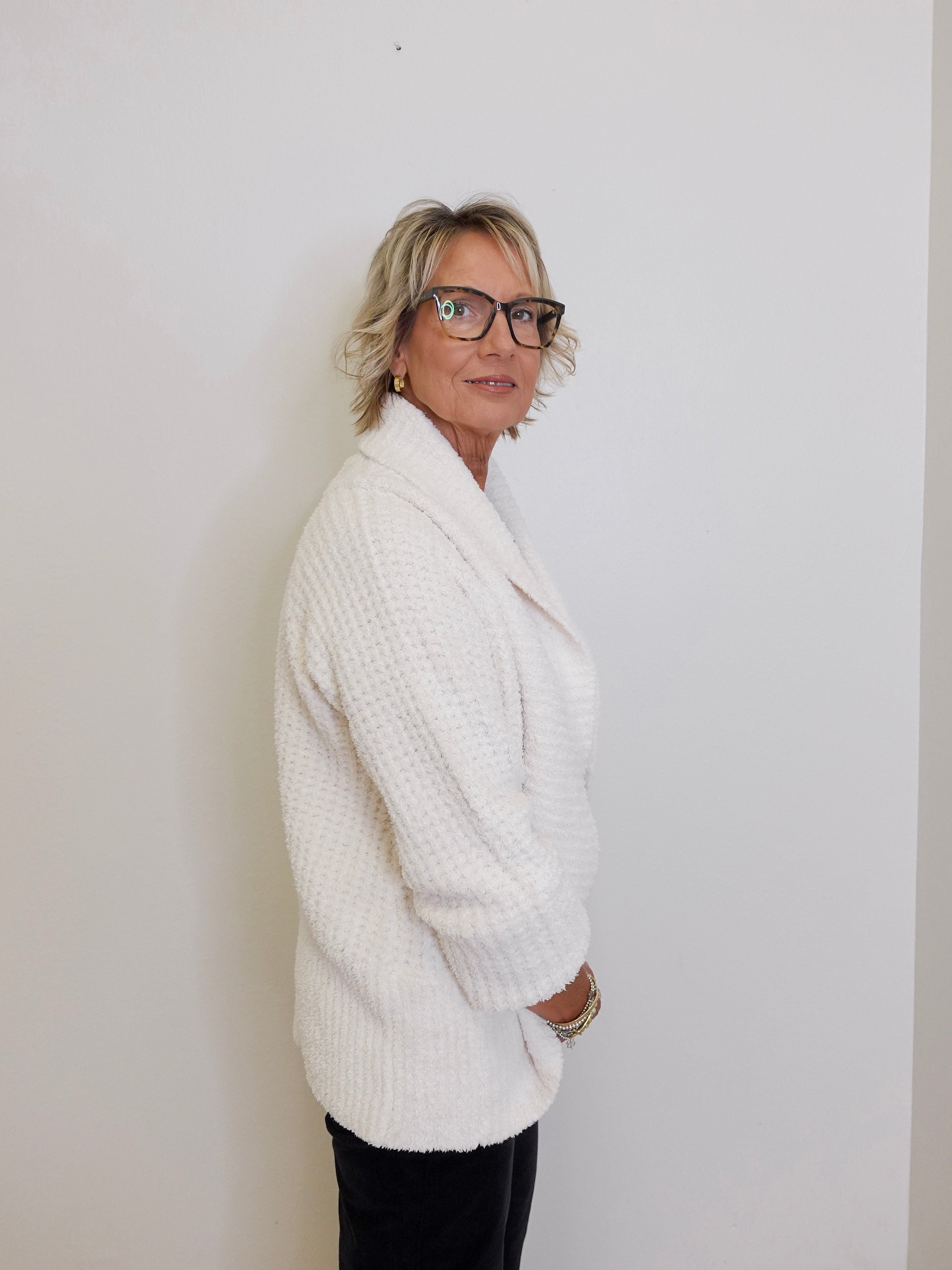 Person wearing a white sweater against a plain background