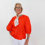 Person wearing an orange blouse with a white background