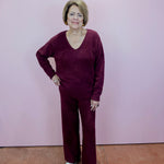 Woman wearing a maroon outfit standing against a plain background