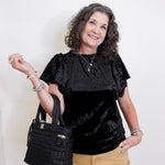 Woman holding a black handbag against a white background