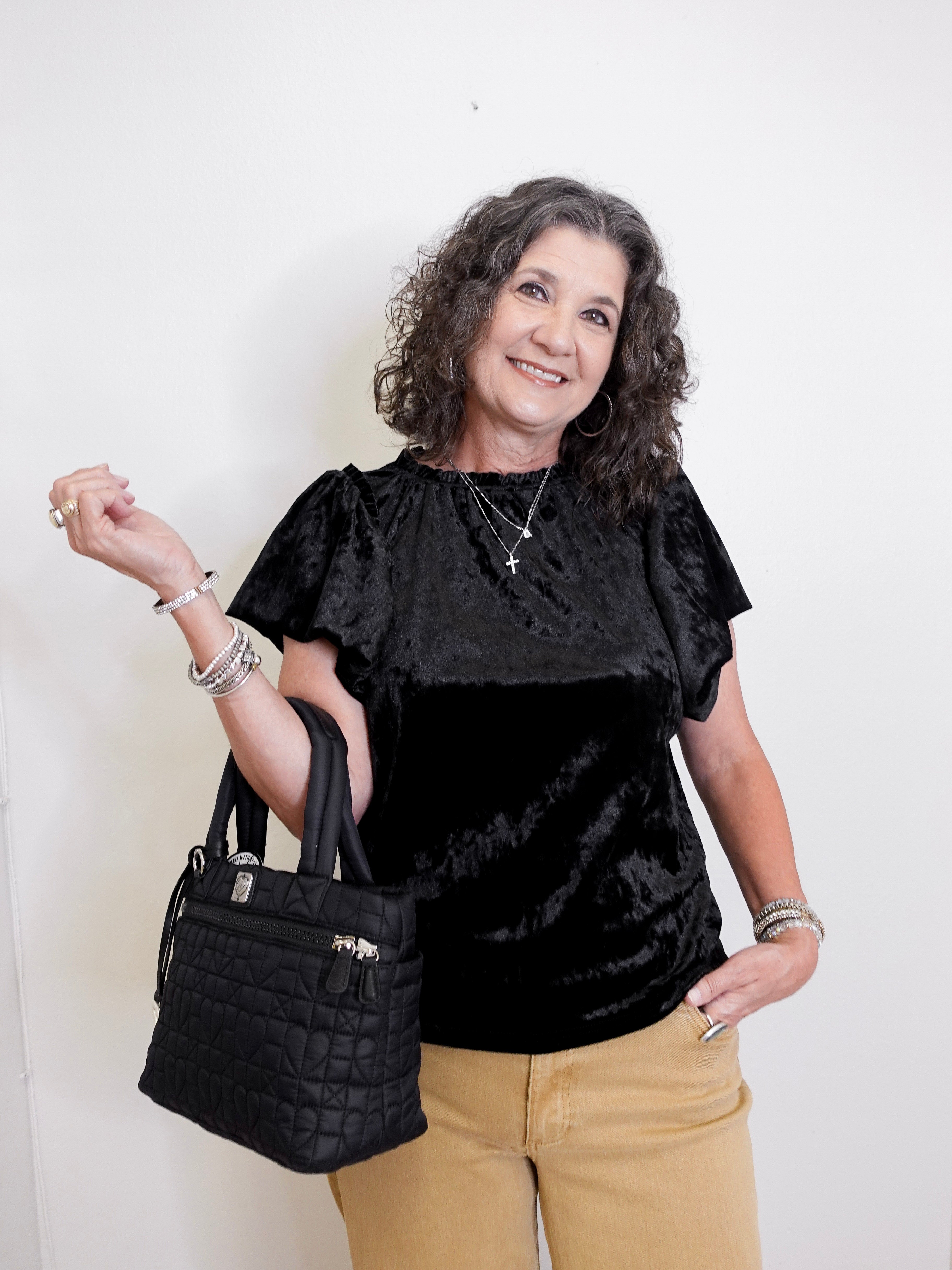 Woman holding a black handbag against a white background