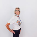 Person wearing a white t-shirt with a colorful graphic and dark jeans on a plain background