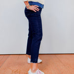 Person wearing a striped sweater, blue jeans, and white sneakers on a plain background