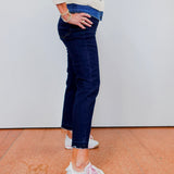 Person wearing a striped sweater, blue jeans, and white sneakers on a plain background