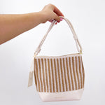 Hand holding a woven bag with a plain background