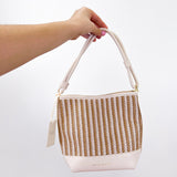 Hand holding a woven bag with a plain background
