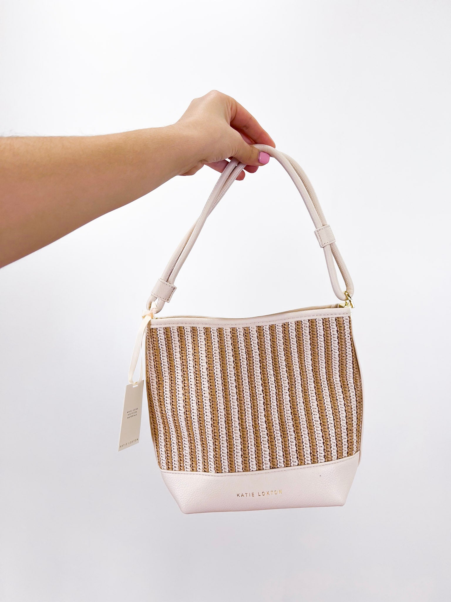 Hand holding a woven bag with a plain background