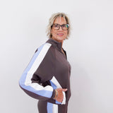 Person wearing a brown tracksuit with white and blue stripes on a plain background