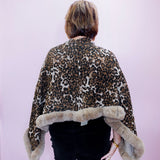 Person wearing a leopard print coat with fur trim on a plain background