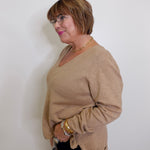 Woman wearing a beige sweater against a white background