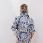 Person wearing a blue patterned shirt against a white background