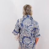 Person wearing a blue patterned shirt against a white background