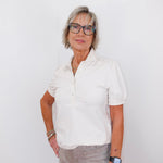 Woman wearing a white shirt and glasses against a white background