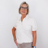 Woman wearing a white shirt and glasses against a white background