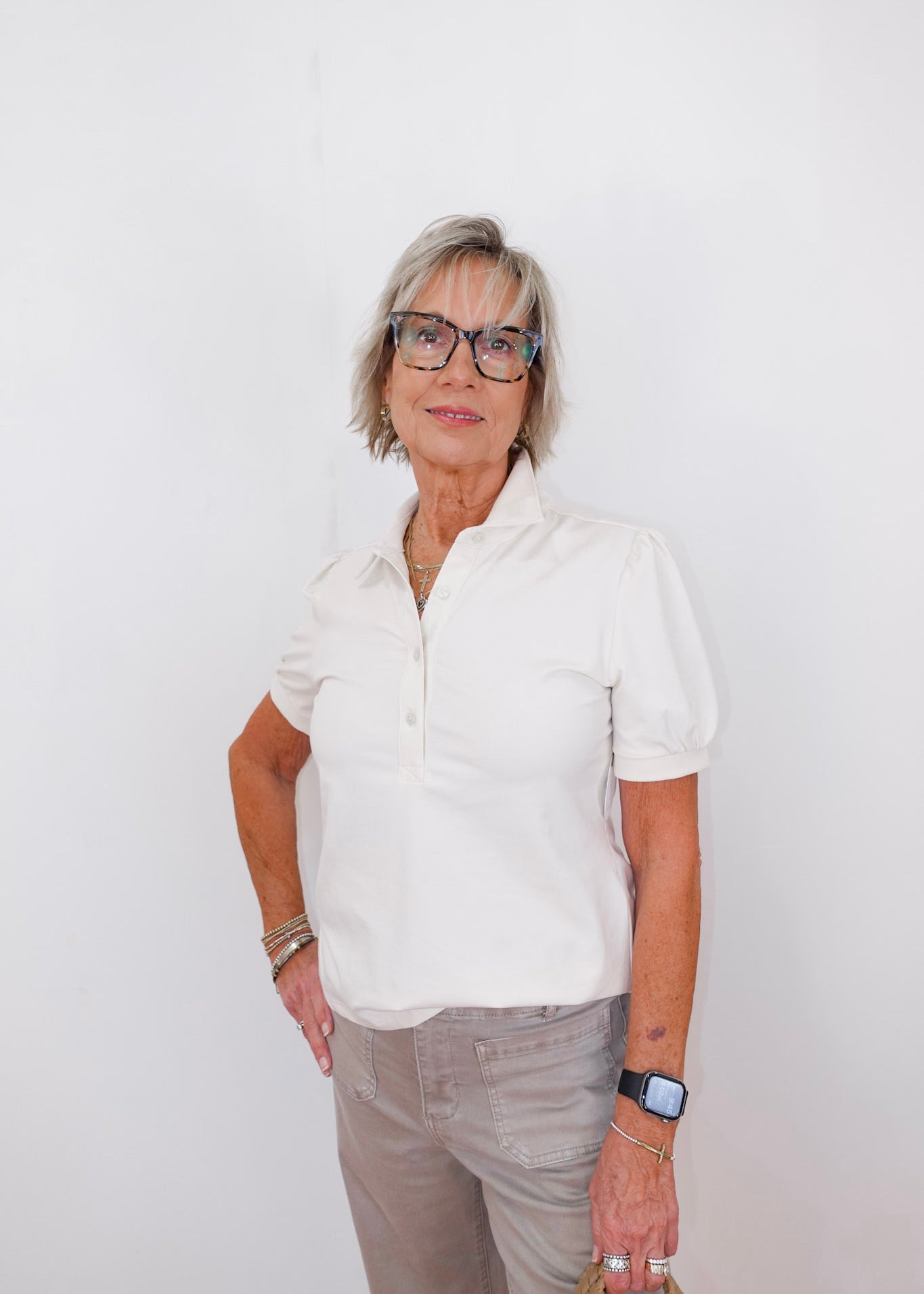 Woman wearing a white shirt and glasses against a white background
