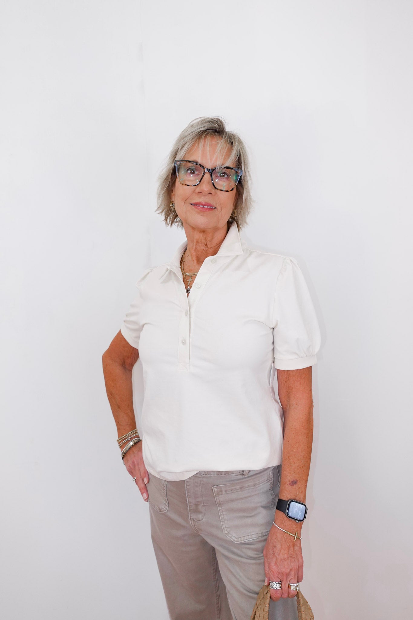 Woman wearing a white shirt and glasses against a white background
