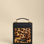 Small black handbag with a leopard print pocket on a beige background