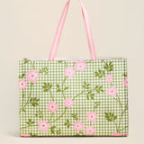 Green gingham tote bag with pink floral pattern on a beige background