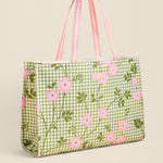 Green gingham tote bag with pink floral pattern on a beige background