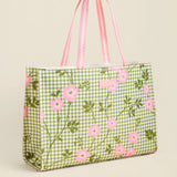 Green gingham tote bag with pink floral pattern on a beige background