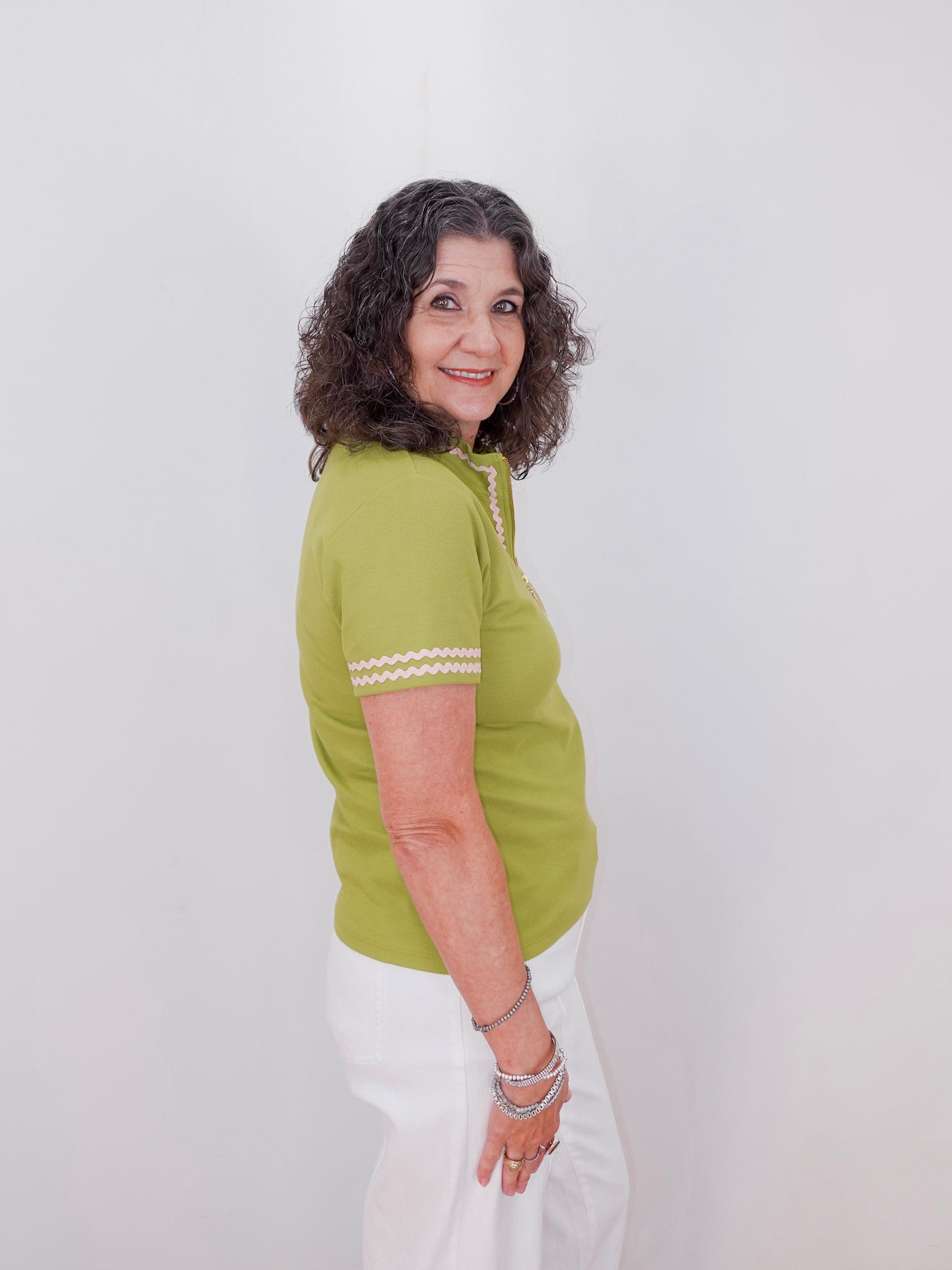 Woman wearing a green top with white trim against a plain background
