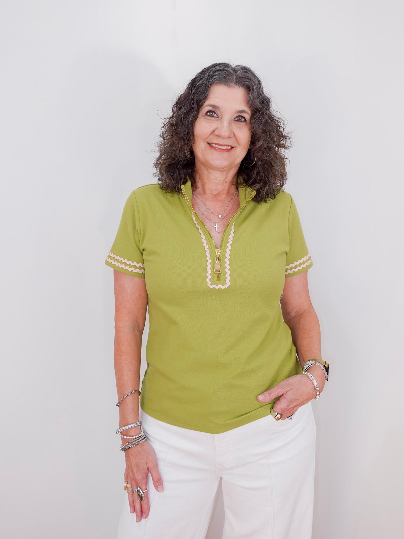 Woman wearing a green shirt with white trim against a plain background