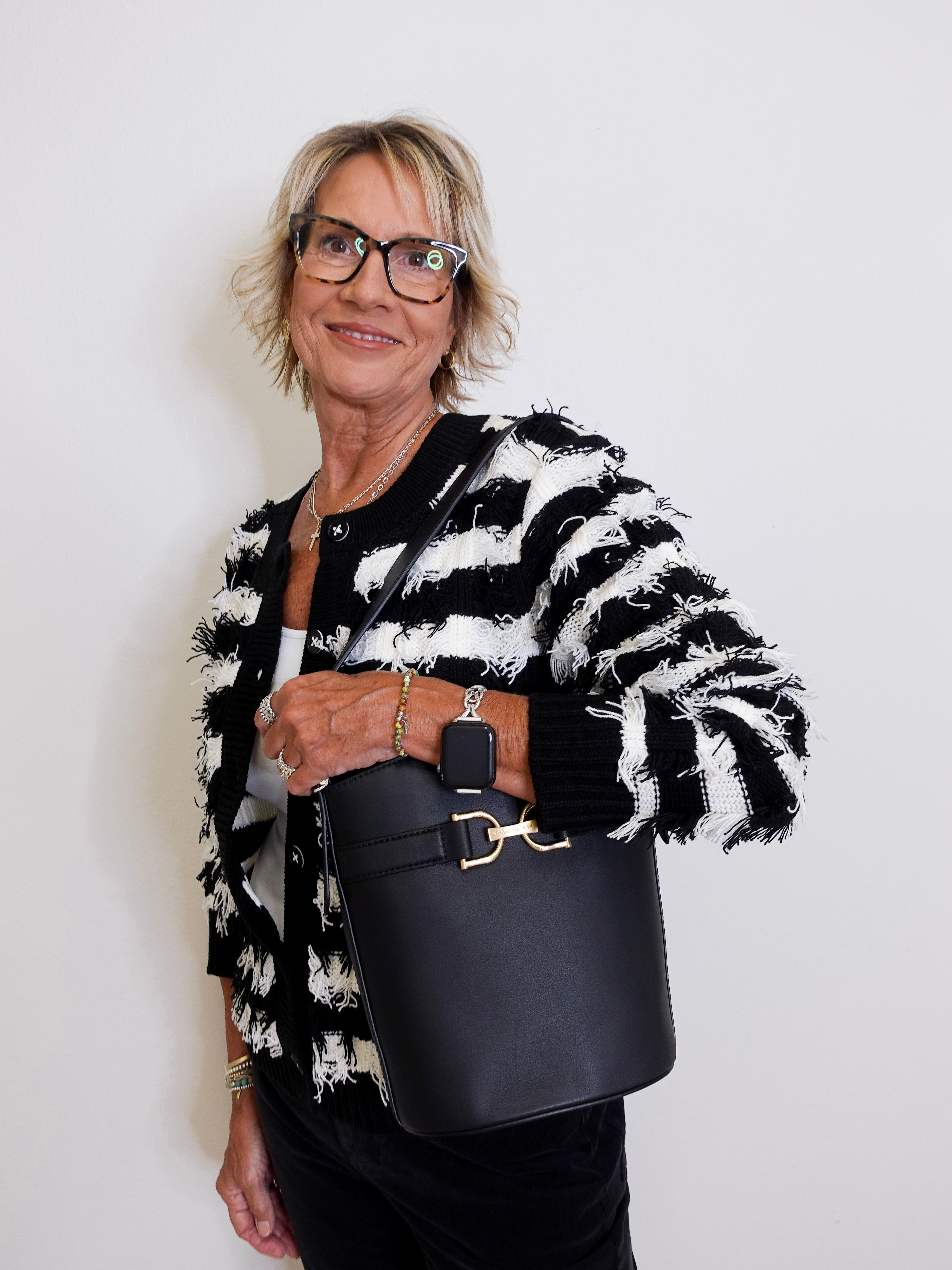 Woman holding a black handbag against a white background