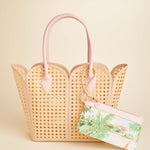 Woven handbag with pink handles on a beige background