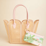Woven handbag with pink handles on a beige background