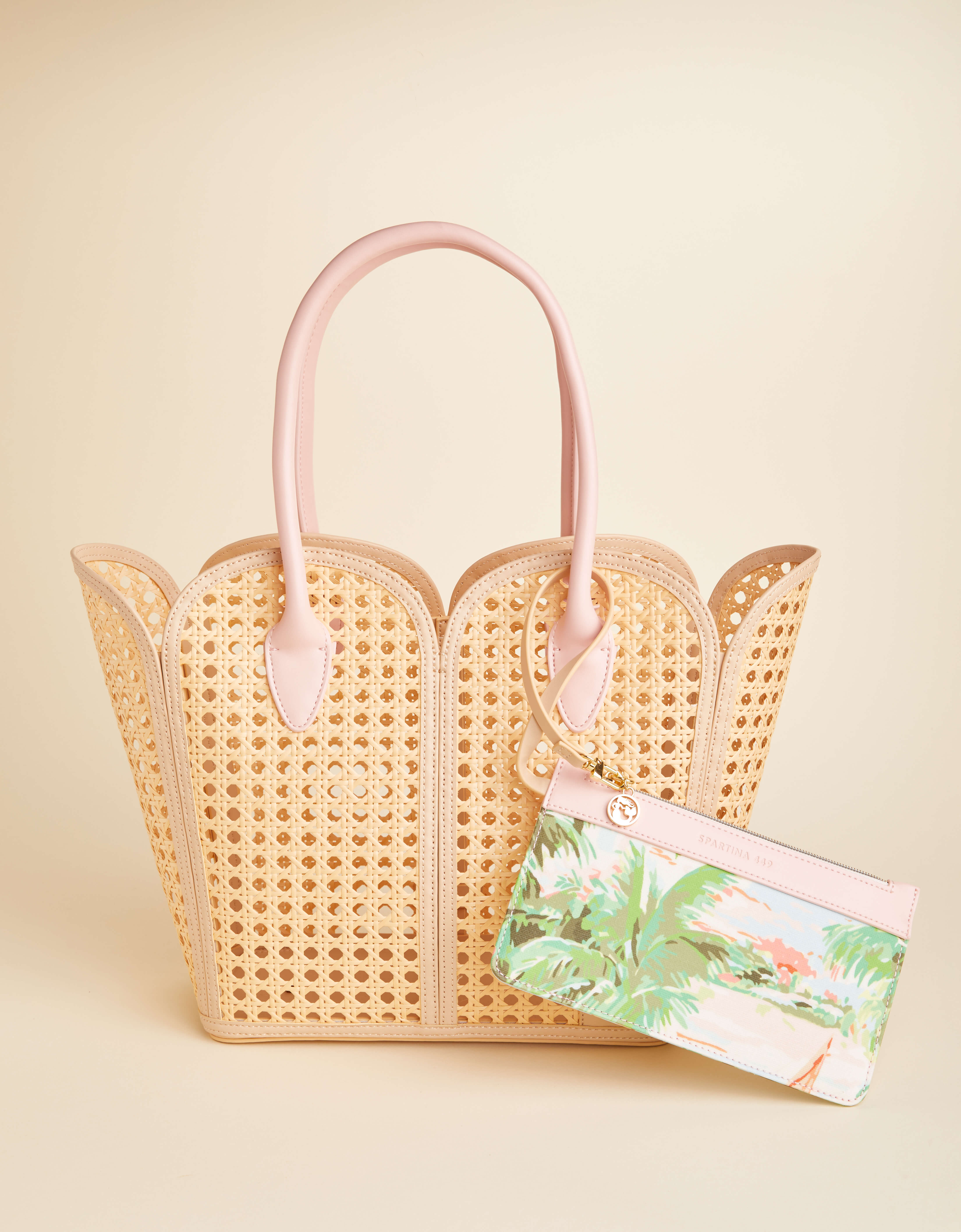 Woven handbag with pink handles on a beige background