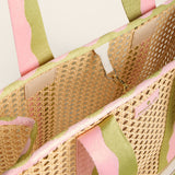 Close-up of a woven bag with pink and green striped handles on a light background