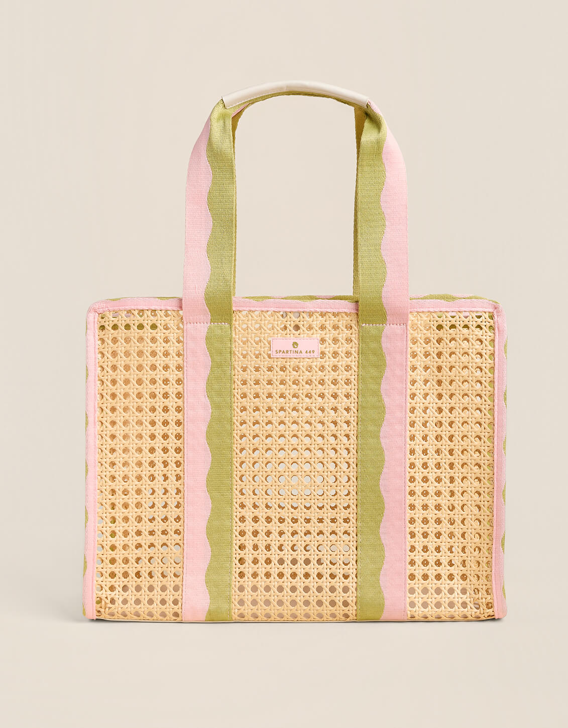 Woven tote bag with pink and green striped handles on a beige background