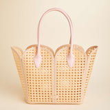 Woven handbag with pink handles on a beige background