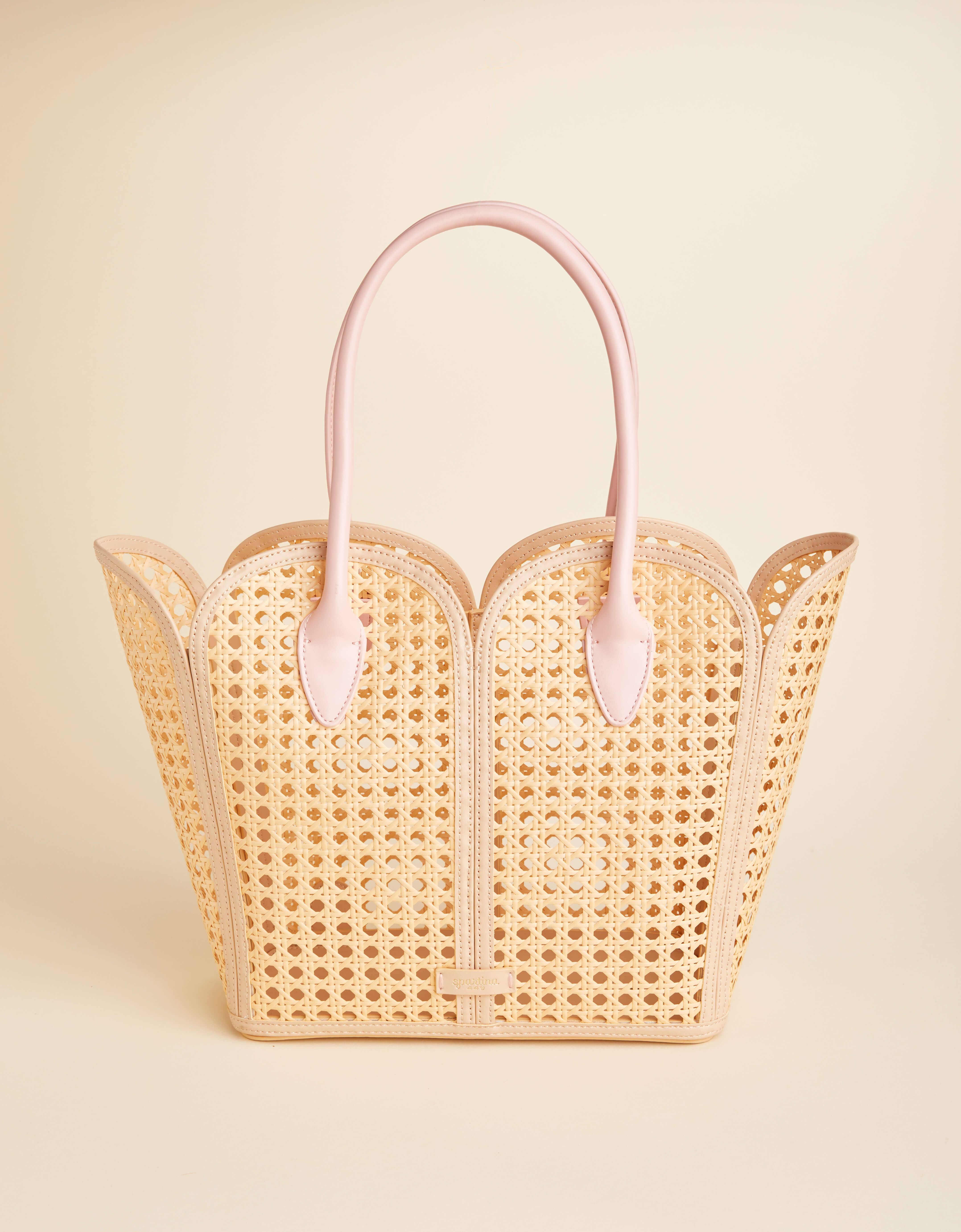Woven handbag with pink handles on a beige background